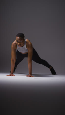 Vertical-Video-Studio-Shot-Of-Young-Woman-Wearing-Gym-Fitness-Clothing-Warming-Up-For-Exercise-1